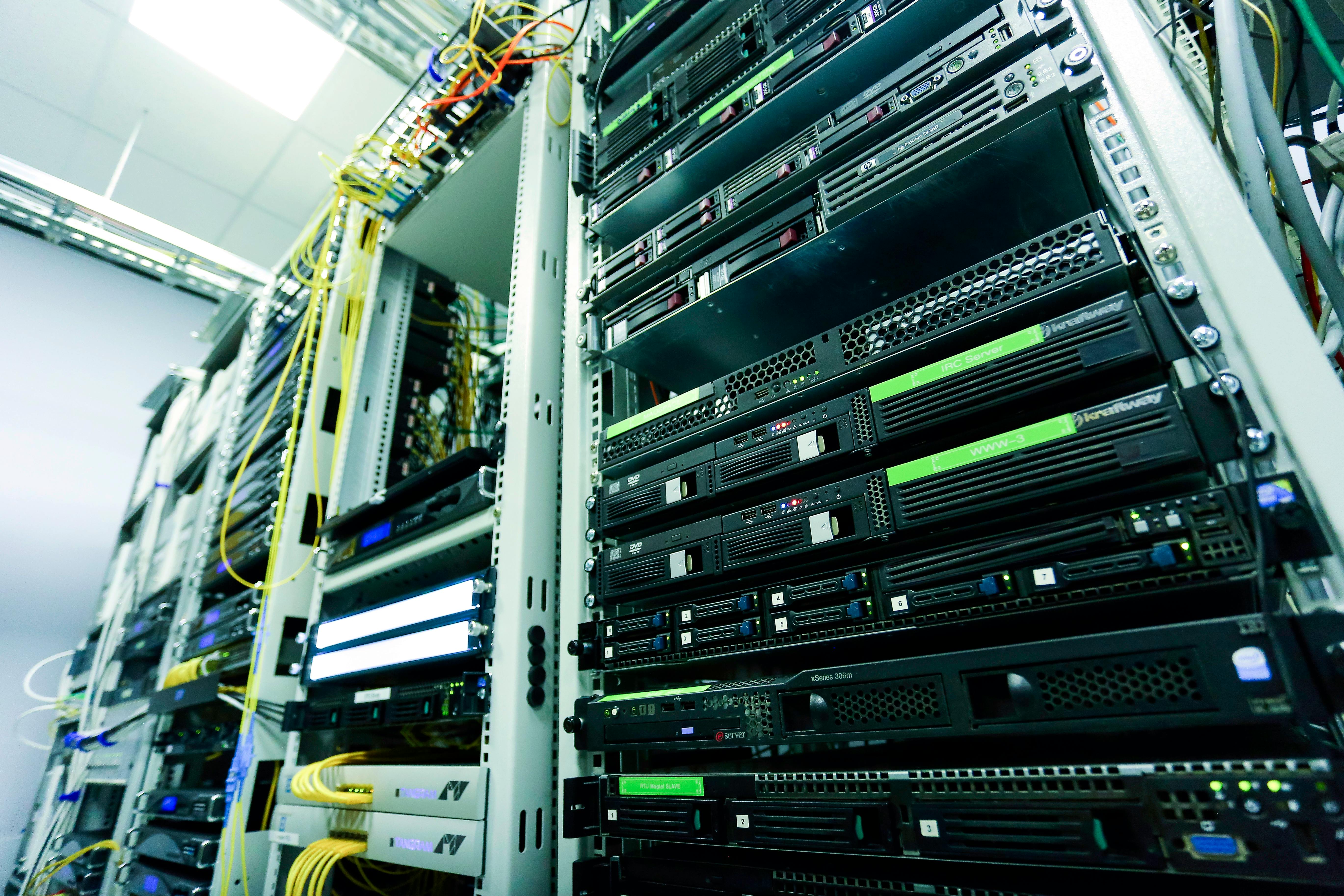 Serverraum mit mehreren Racks mit Netzwerkgeräten und Kabeln.